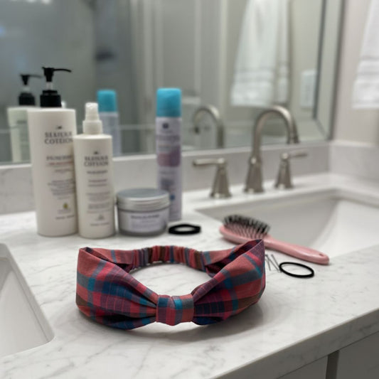 Plaid  bow headband on a bathroom counter with toiletries and a sink in the background